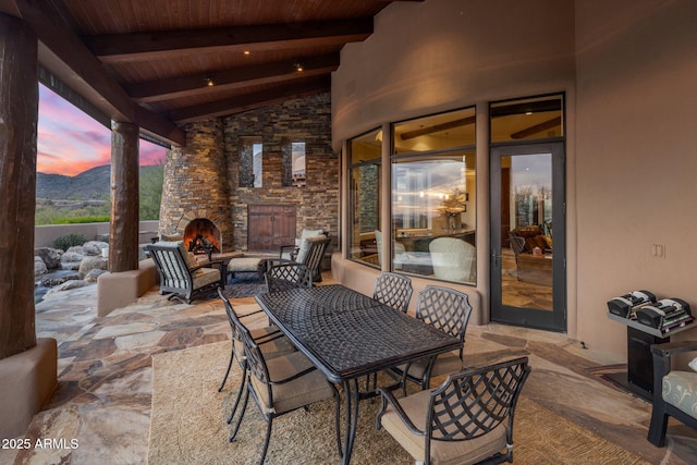 patio terrace at dusk featuring an outdoor stone fireplace