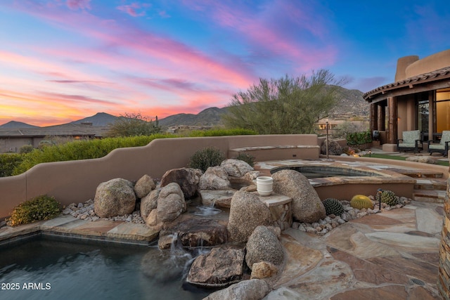 pool at dusk with a mountain view and a patio area