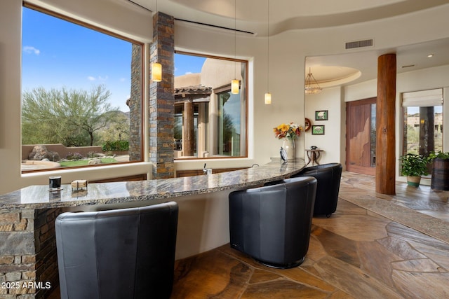 bar with pendant lighting and light stone countertops