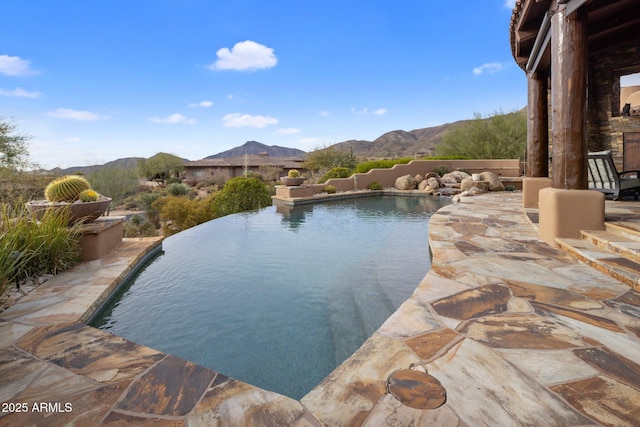 view of swimming pool featuring a mountain view, a patio area, and an outdoor fireplace