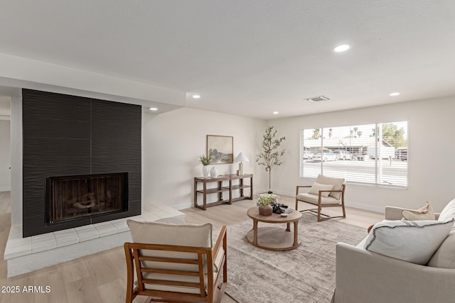 living room with light hardwood / wood-style floors and a tile fireplace