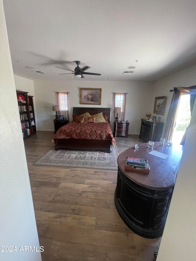 bedroom featuring wood-type flooring, multiple windows, and ceiling fan