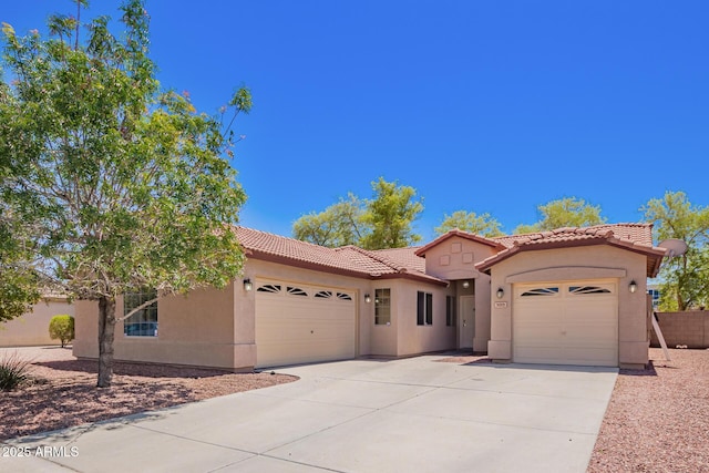 mediterranean / spanish-style home featuring a garage, a tile roof, stucco siding, and driveway