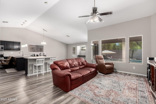 living area with wood finished floors, a ceiling fan, visible vents, and vaulted ceiling