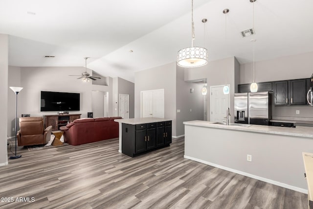 kitchen with stainless steel fridge, a sink, vaulted ceiling, and light countertops