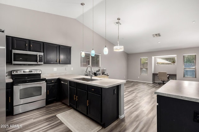 kitchen with stainless steel appliances, dark cabinetry, visible vents, a sink, and a peninsula