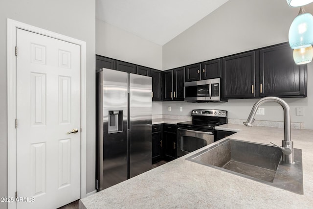 kitchen featuring a sink, stainless steel appliances, light countertops, vaulted ceiling, and dark cabinetry