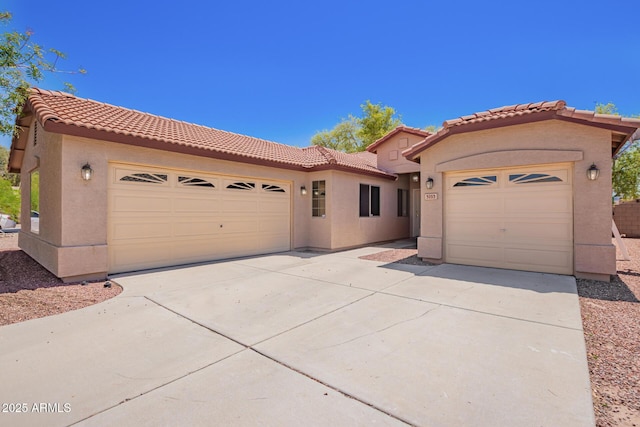mediterranean / spanish home with driveway, a tile roof, stucco siding, and a garage
