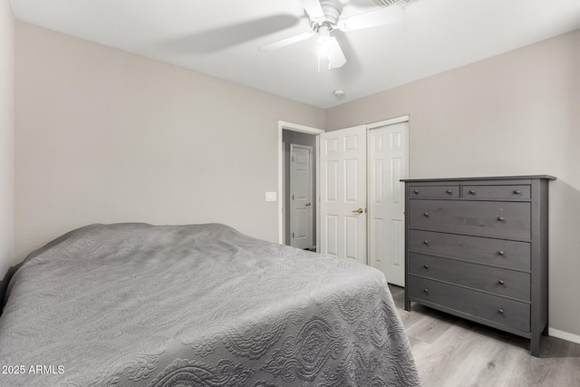 bedroom with ceiling fan, baseboards, light wood finished floors, and a closet