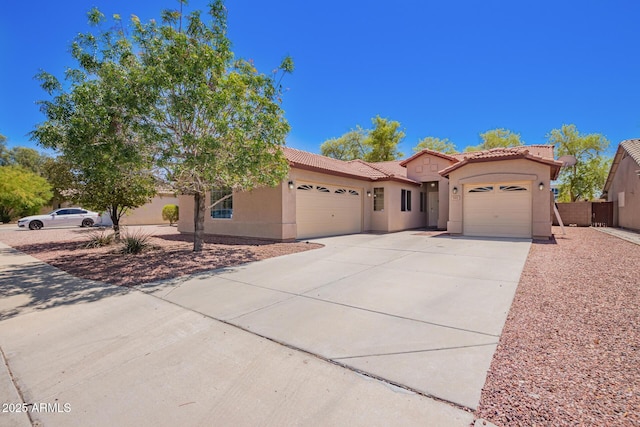 mediterranean / spanish house with stucco siding, driveway, a tiled roof, and an attached garage