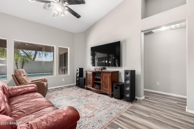 living area featuring baseboards, light wood-type flooring, ceiling fan, and high vaulted ceiling