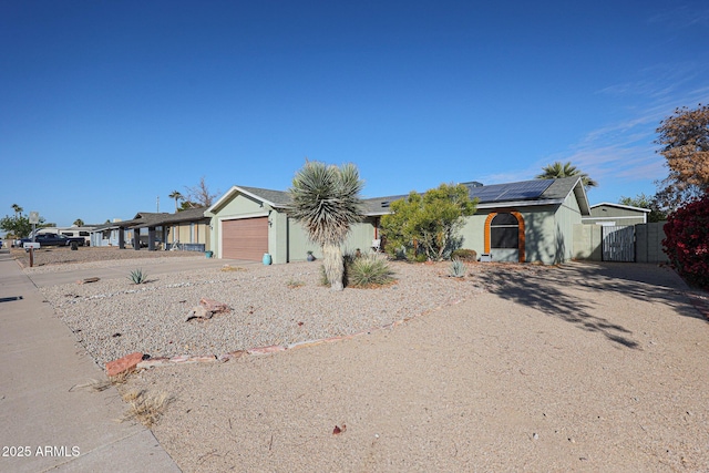 ranch-style house featuring a garage and solar panels