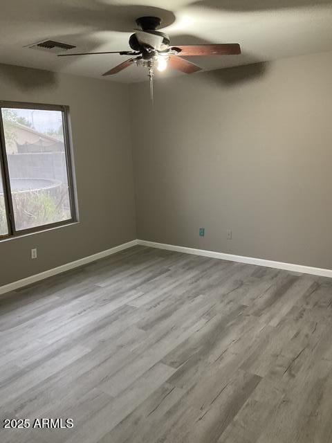 empty room featuring a ceiling fan, wood finished floors, and baseboards