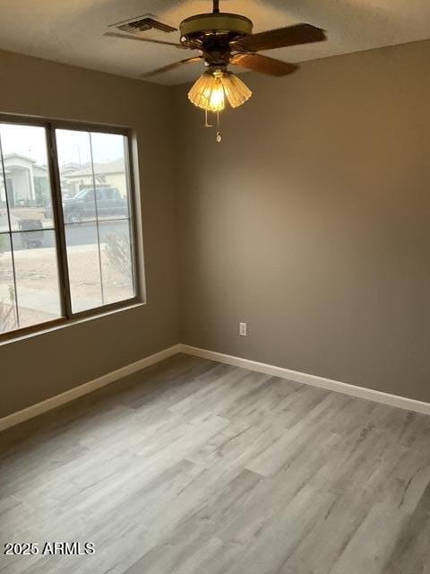 empty room with baseboards, wood finished floors, and a ceiling fan