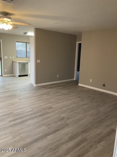 spare room featuring baseboards, wood finished floors, and ceiling fan