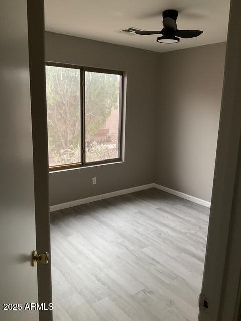 spare room with ceiling fan, wood finished floors, and baseboards