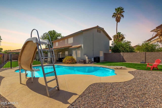 view of swimming pool with a water slide, a fenced backyard, a fenced in pool, cooling unit, and a patio area