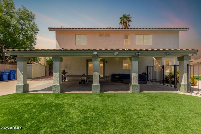 back of property at dusk featuring a patio area, fence, and a yard