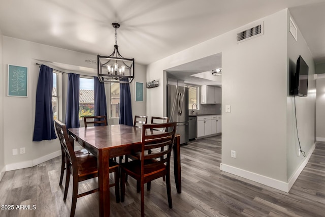 dining room featuring baseboards, a notable chandelier, wood finished floors, and visible vents