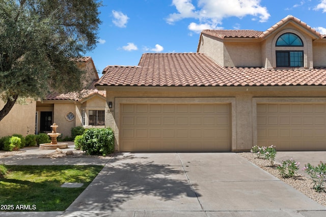 mediterranean / spanish home with concrete driveway, stucco siding, a tile roof, and an attached garage