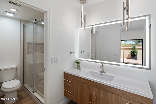 bathroom featuring toilet, a stall shower, vanity, wood finished floors, and baseboard heating