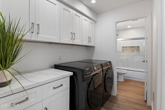 clothes washing area with washer and dryer, cabinet space, light wood-type flooring, and recessed lighting