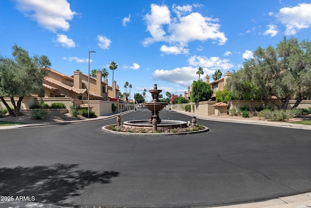 view of asphalt road featuring sidewalks, street lights, curbs, and a residential view
