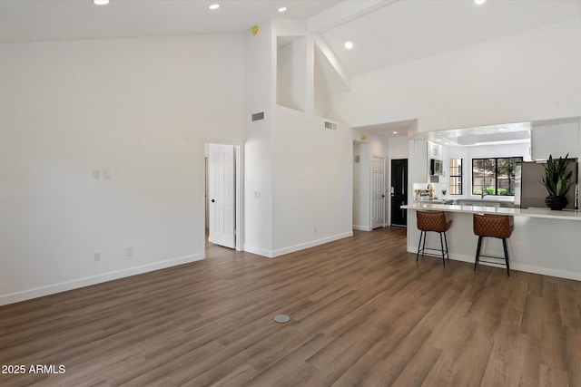 living room featuring high vaulted ceiling, wood finished floors, baseboards, and recessed lighting