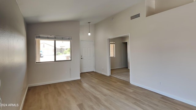 spare room with light hardwood / wood-style flooring and high vaulted ceiling