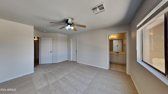 unfurnished bedroom with connected bathroom, light carpet, and ceiling fan