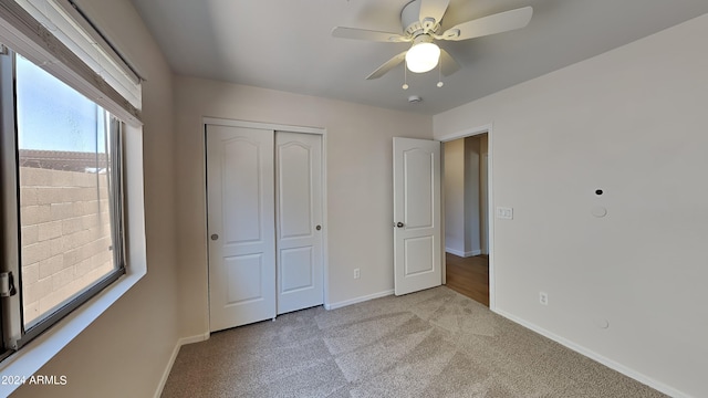 unfurnished bedroom with light colored carpet, a closet, and ceiling fan