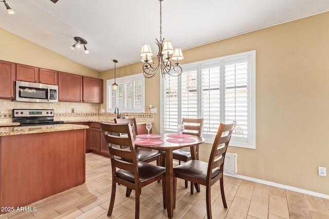 dining area featuring light wood-type flooring, baseboards, lofted ceiling, and a notable chandelier