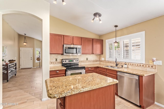 kitchen with a sink, appliances with stainless steel finishes, tasteful backsplash, and vaulted ceiling