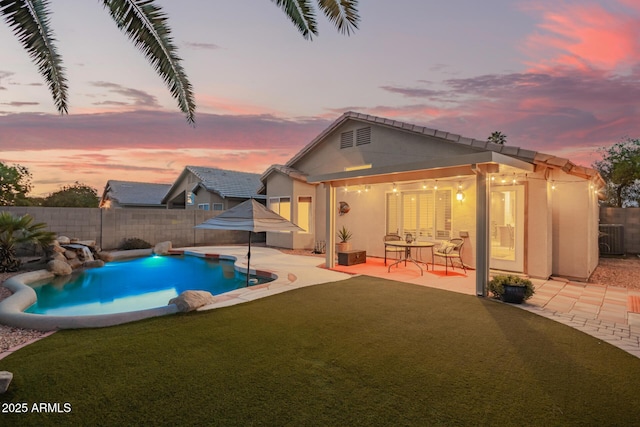 pool at dusk featuring a lawn, a fenced in pool, a fenced backyard, and a patio area