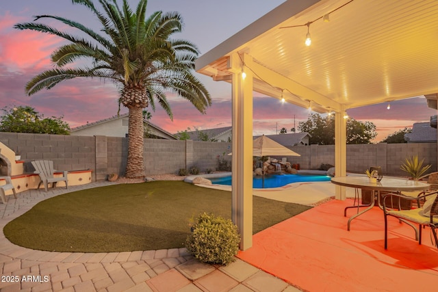 patio terrace at dusk featuring a fenced in pool and a fenced backyard