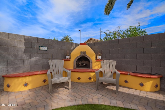 view of patio featuring fence and exterior fireplace
