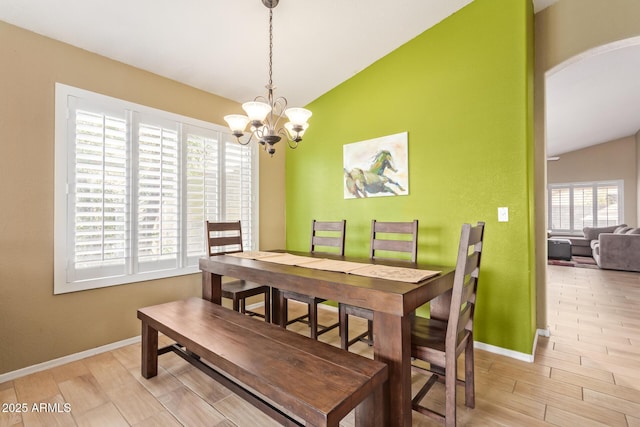 dining space featuring baseboards, lofted ceiling, and a notable chandelier