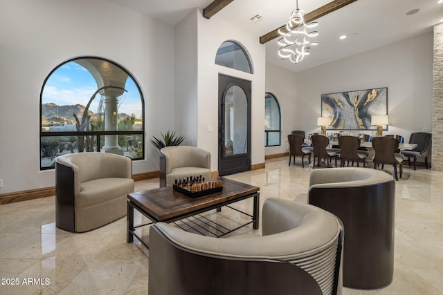 living room with a towering ceiling, beam ceiling, and a notable chandelier