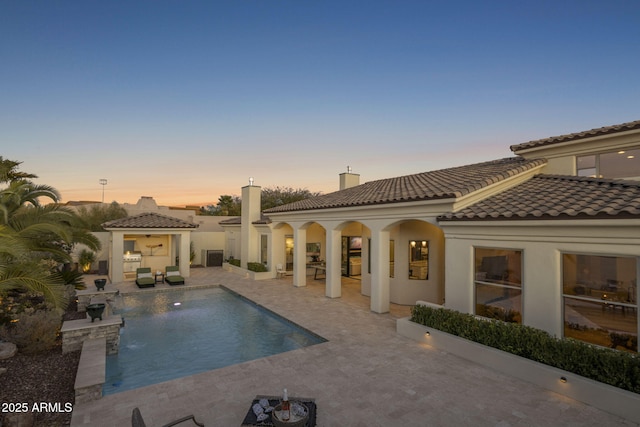 pool at dusk featuring a patio area