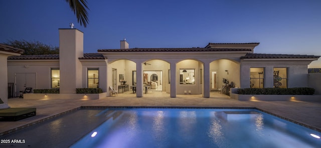 pool at dusk with a patio area