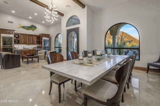 dining area with a chandelier, a mountain view, a towering ceiling, and beamed ceiling