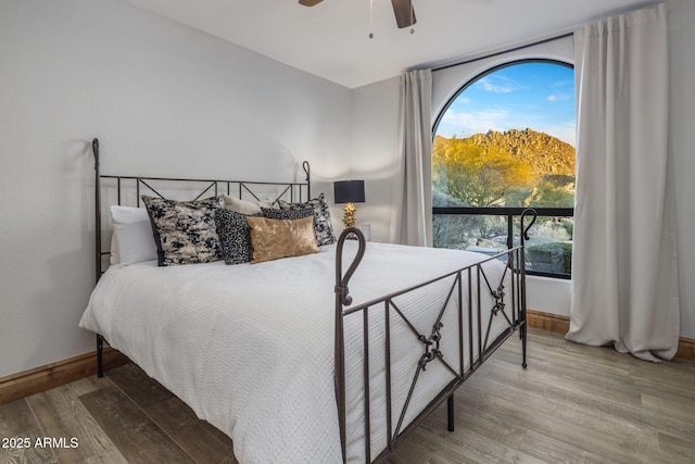 bedroom featuring ceiling fan, wood-type flooring, and multiple windows