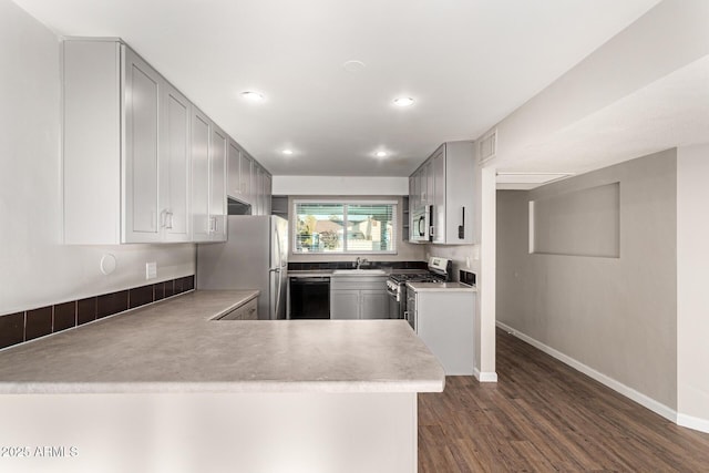 kitchen with sink, dark wood-type flooring, stainless steel appliances, and kitchen peninsula