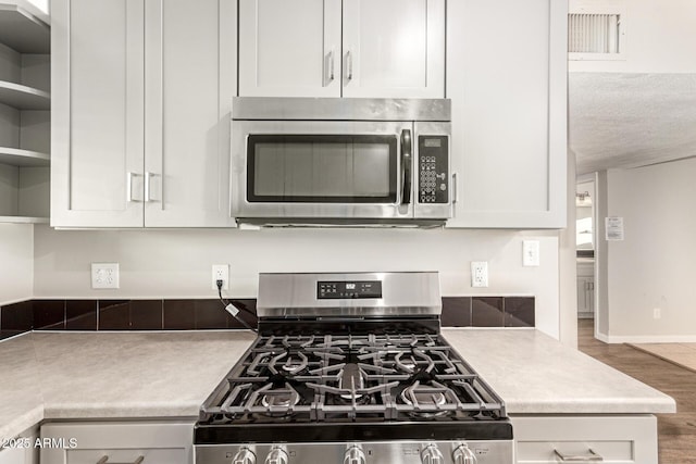 kitchen featuring appliances with stainless steel finishes, hardwood / wood-style floors, a textured ceiling, and white cabinets