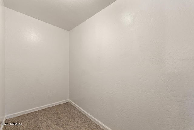 carpeted empty room with lofted ceiling