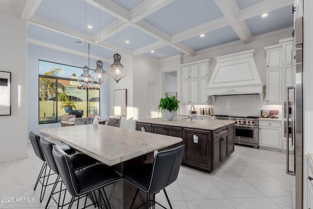 kitchen with a center island with sink, custom range hood, coffered ceiling, dark brown cabinets, and high end range