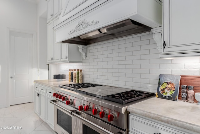 kitchen with premium range hood, decorative backsplash, range with two ovens, and white cabinets