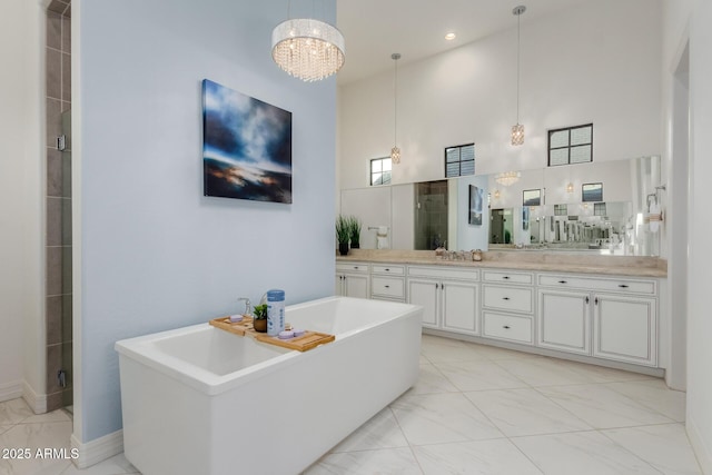 bathroom with a sink, a high ceiling, a shower stall, double vanity, and a freestanding bath