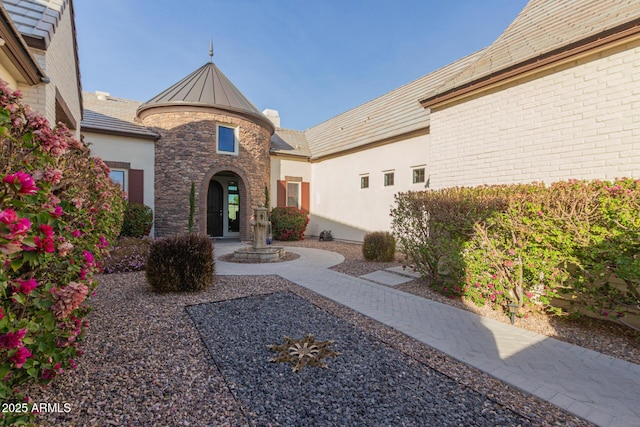 exterior space featuring stucco siding, stone siding, metal roof, and a standing seam roof