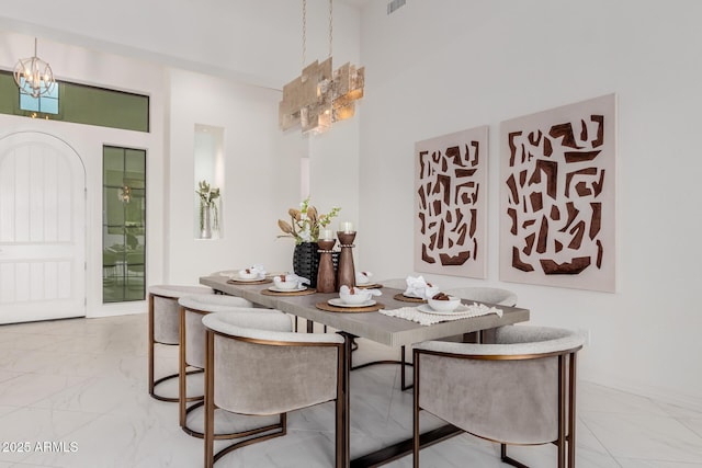 dining space with marble finish floor and an inviting chandelier